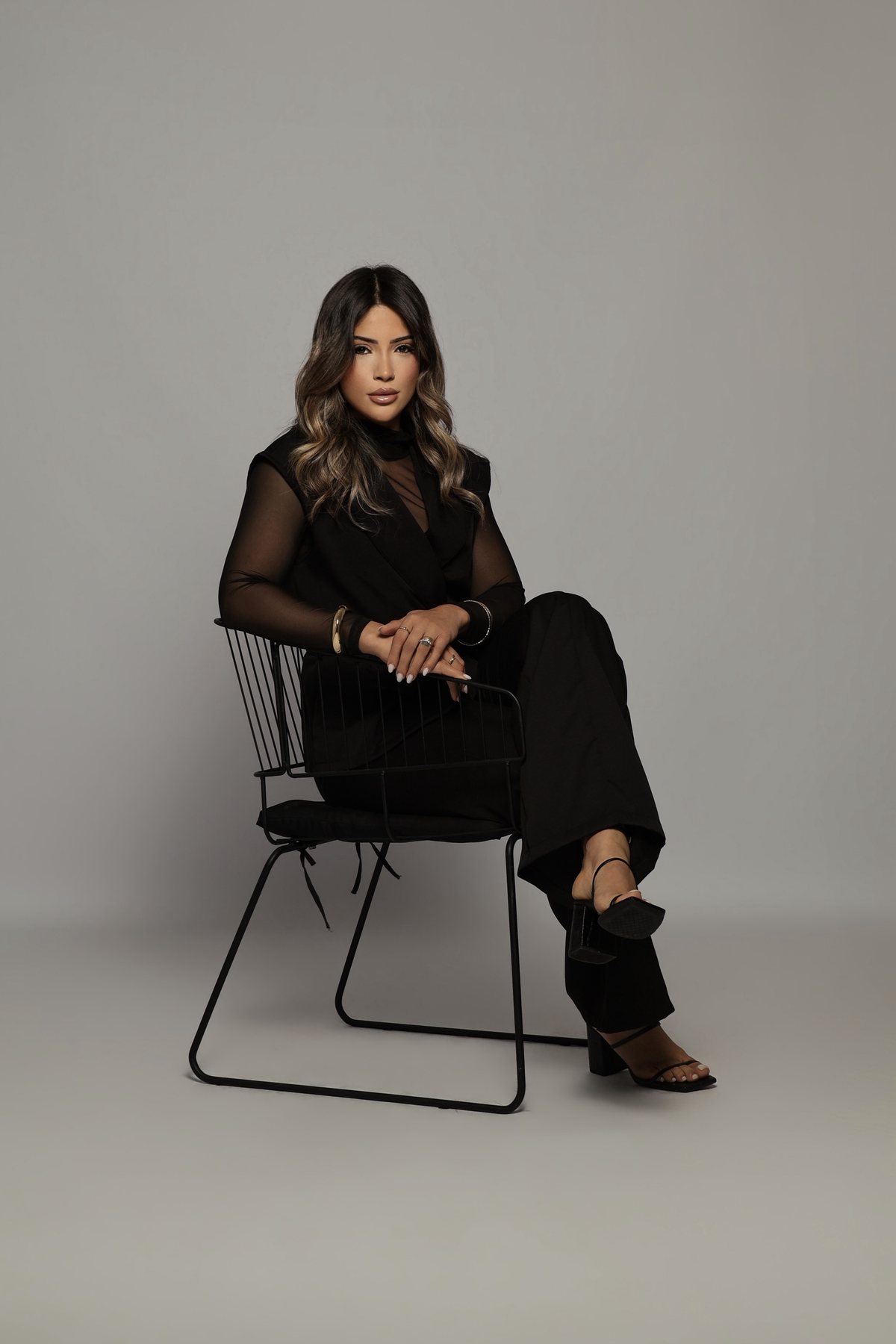 Dra. Ingrid Santana sentada em uma poltrona, de roupa preta